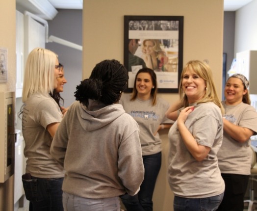 Group of dental team members laughing together during community event