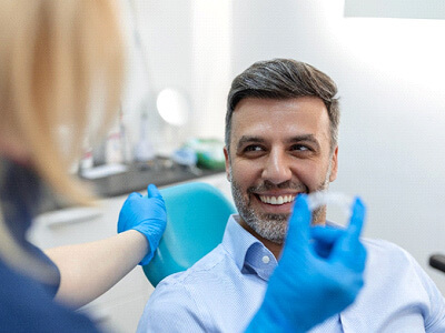 A dentist showing her male patient an invisalign tray
