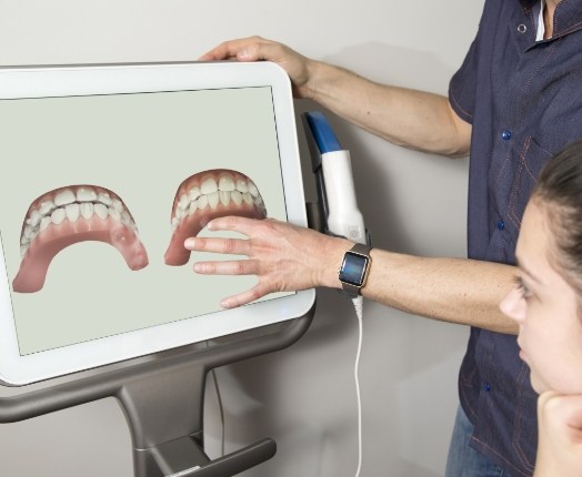 Dentist and dental patient looking at Invisalign treatment plan on computer screen