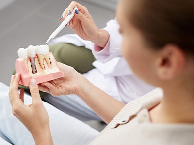 A patient holding an enlarged dental implant model