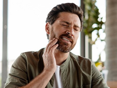 A bearded man suffering from a toothache