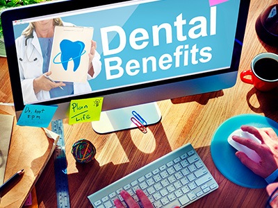 A dental insurance plan, a pen, and other items on a wooden desk