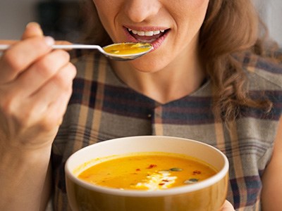 A woman eating from a bowl of soup