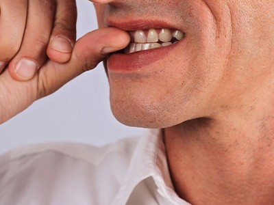 A closeup of a man biting his fingernails