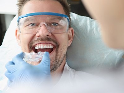A man receiving a clear plastic mouthguard from his dentist