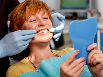 A senior woman admiring her smile with a hand mirror