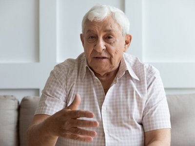 An older man sitting on a couch and speaking