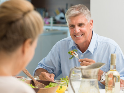 An older couple eating salad at a dining table