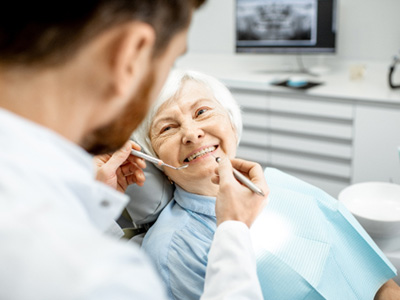 A smiling, elderly woman receiving dental care