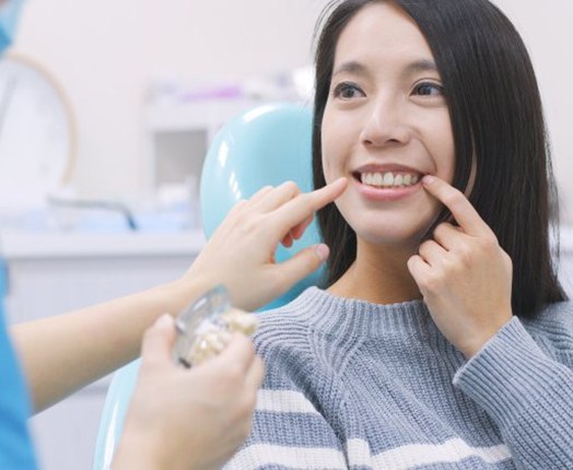 Woman pointing to her teeth while talking to dentist