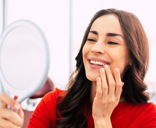 Woman admiring her new smile in small mirror