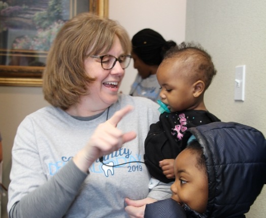 Dental team member laughing with children at community event