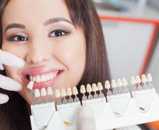 Woman's smile compared with dental bonding shade options during cosmetic dentistry visit