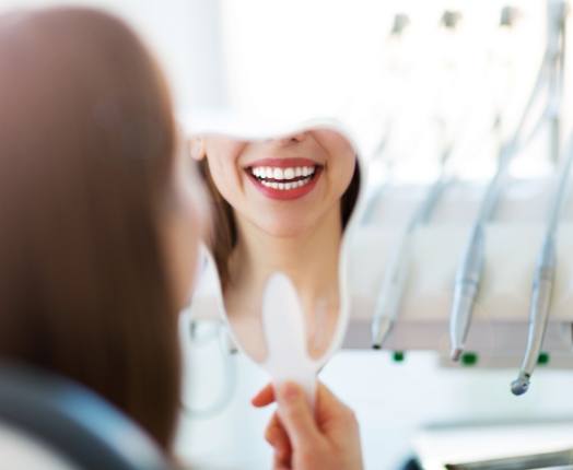 Woman looking in mirror after smile makeover