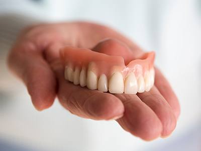 A closeup of a hand holding a removable denture