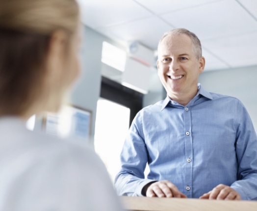 Dental patient checking in at dental office reception desk