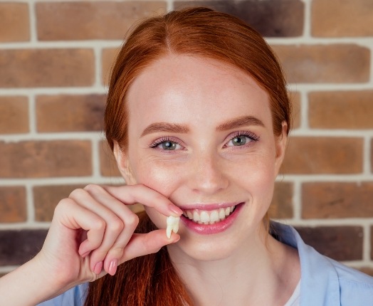 Woman holding up tooth after extraction