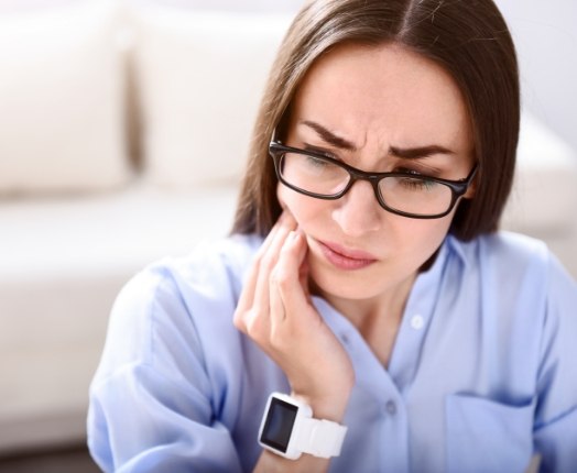 Woman holding jaw in pain before T M J therapy