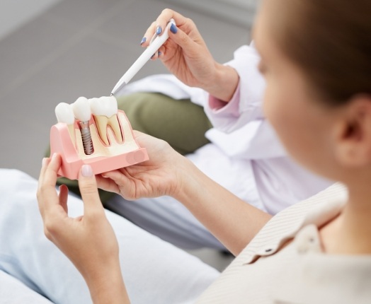 Dentist and dentistry patient looking at dental implant model