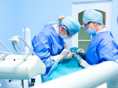 Dentists providing dental implant tooth replacement treatment