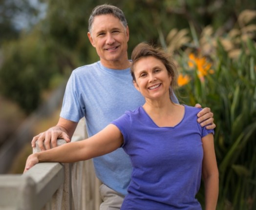 Man and woman smiling together after dental implant tooth replacement