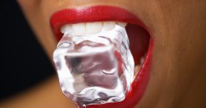 woman in red lipstick biting into ice cube