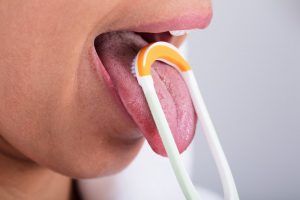 woman scraping tongue before visiting dentist in Temple