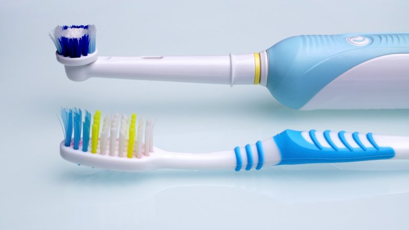 Manual toothbrush next to an electric one