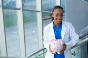 dentist in Temple holding a pink piggy bank 