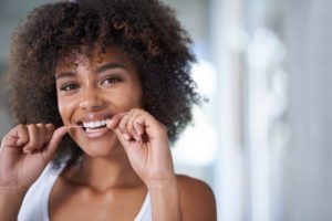 young woman smiling while flossing 