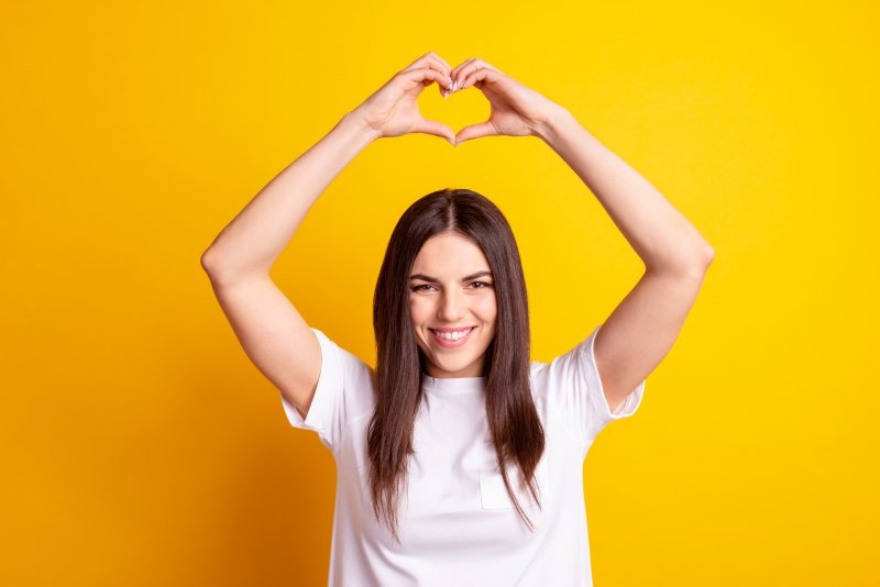 person smiling and making a heart with their fingers