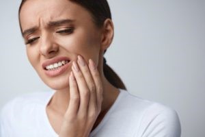 Woman experiencing tooth pain from a cavity.