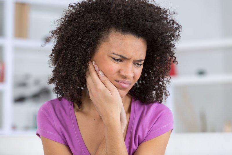 person experiencing dental emergency holding cheek