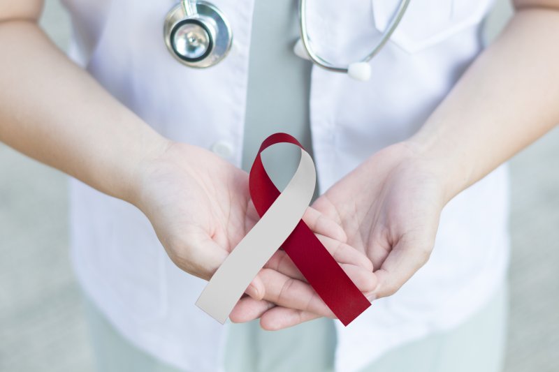 A doctor with a red and white ribbon, which symbolizes Oral Cancer Awareness Month