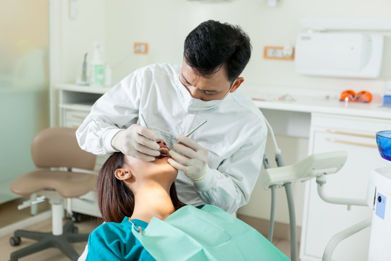 A dentist performing an oral cancer screening on a woman