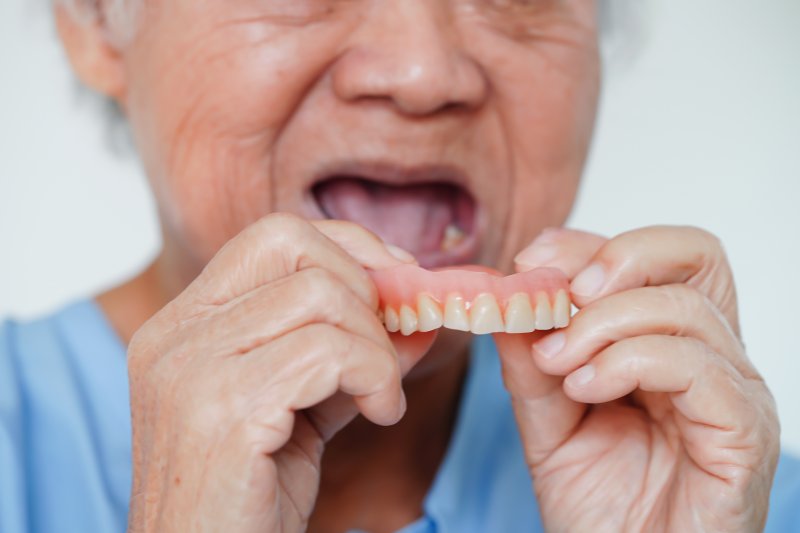 An older woman trying to put her dentures in her mouth