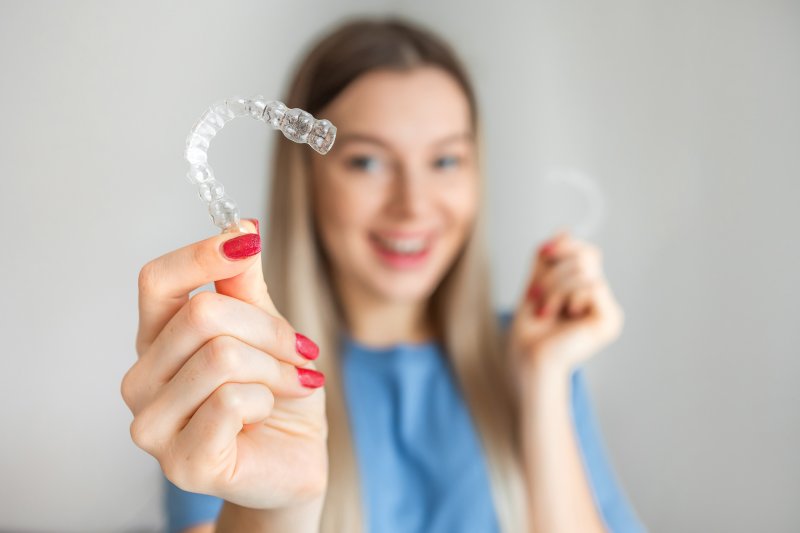 A blurred woman holding Invisalign aligners in the foreground