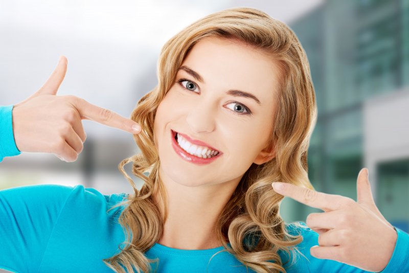 A smiling woman pointing out the results of her cosmetic dental work