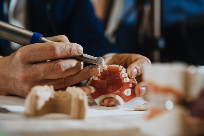 A dental technician processing a cast of the jaws